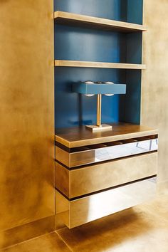 a gold and blue shelf with a lamp on it