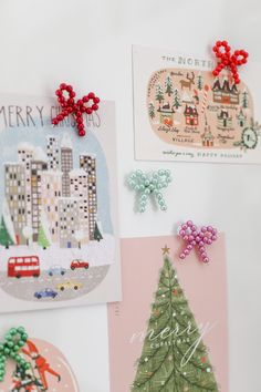 christmas cards and magnets are displayed on a white surface with red bows, green trees, and cityscape