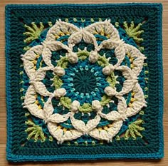 a crocheted square with an intricate design on the center and sides in blue, green, white and yellow