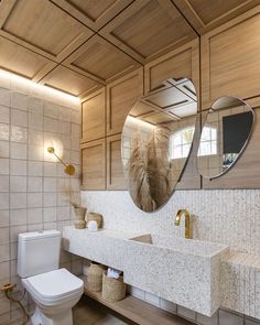 a white toilet sitting next to a bathroom sink under a large mirror on the wall