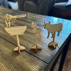 three wooden toy animals sitting on top of a wooden table next to each other,