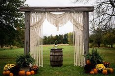 an outdoor wedding ceremony with pumpkins and macrami hanging from the arbor,