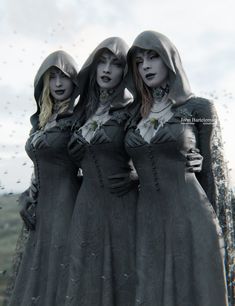 three women dressed in gothic clothing standing next to each other with rain drops falling on them