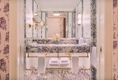 a bathroom with marble counter tops and gold accents on the walls, along with white towels