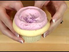 two hands holding a cupcake with pink frosting