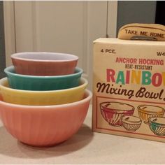 four bowls are stacked in front of a box on the kitchen counter next to each other