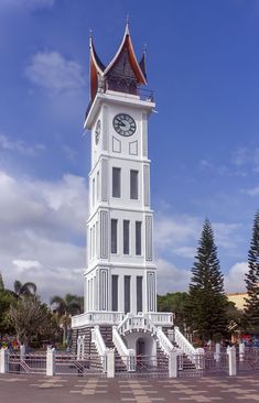 a tall white clock tower sitting on the side of a road with stairs leading up to it