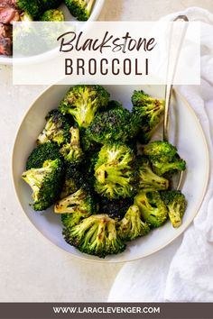 a white bowl filled with broccoli on top of a table next to a fork