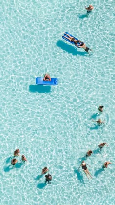 several people are swimming in the water and one person is floating on a blue raft