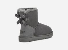 Our iconic boot has been updated with the addition of delicate, silky bows for a charming, feminine aesthetic. Constructed from soft sheepskin, this multi-functional boot integrates a strong, feather-light sole to amplify cushioning and grip. It's an ideal match for a wide range of outfits, from athleisure wear to flowing dresses.This product was made in a factory that supports women in our supply chain with the help of HERproject, a collaborative initiative that creates partnerships with brands Ugg Mini Bailey Bow, Grey Uggs, Uggs With Bows, Mini Baileys, Flowy Dresses, Ugg Mini, Ugg Bailey, Bailey Bow, Sheepskin Boots