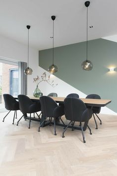 a dining room table with chairs and lights hanging from the ceiling