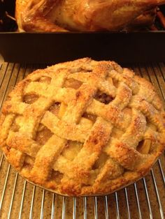 an apple pie sitting on top of a metal rack next to a roasting pan