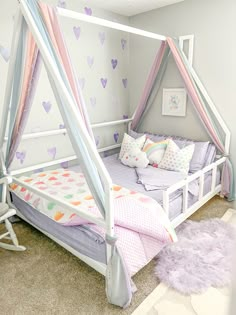 a child's bed with pink, blue and white canopy