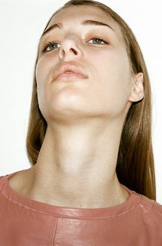 a woman wearing a brown leather top looking up at something in the air with her eyes closed