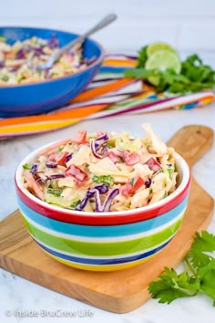 a colorful bowl filled with coleslaw salad on top of a wooden cutting board