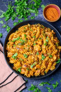 a bowl filled with pasta and garnished with parsley next to some spices