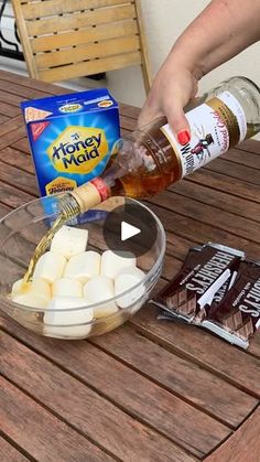 someone is pouring marshmallows into a bowl on a wooden table with chips