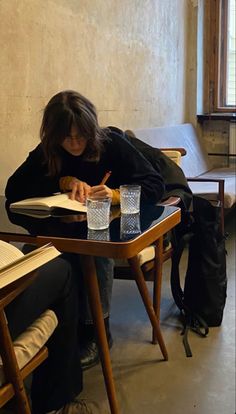 a woman sitting at a table writing in a book