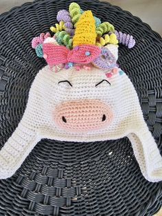 a crocheted hat with a cow's head on it, sitting on top of a wicker basket