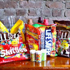 three bags of candy sitting next to each other on a wooden table with a brick wall in the background