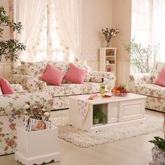 a living room filled with lots of furniture and flowers on the couches in front of a window