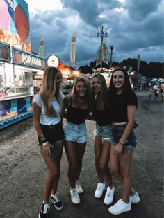 three girls standing next to each other at an amusement park