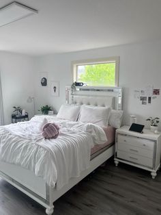 a white bed sitting in a bedroom on top of a hard wood floor next to a window