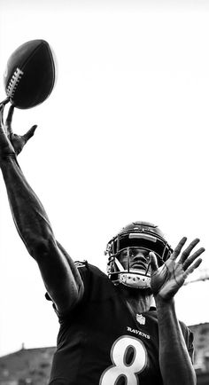 a black and white photo of a football player catching a ball in the air with his hands