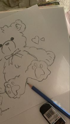 a drawing of a teddy bear on paper with a cell phone next to it,