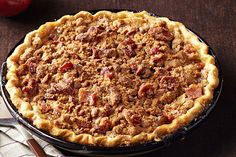 a pie sitting on top of a wooden table next to a knife and fork in front of it