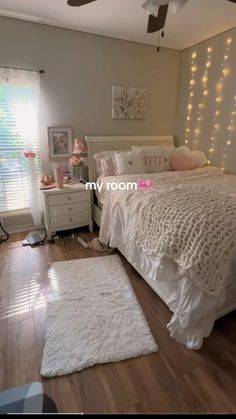 a bedroom with white bedding and lights on the wall above the bed is shown in this image