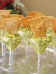 small glasses filled with guacamole and tortilla chips