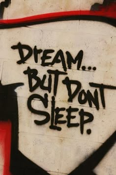 graffiti on the side of a building reads, dream but don't sleep