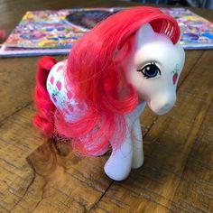 a toy pony with pink hair on top of a wooden table