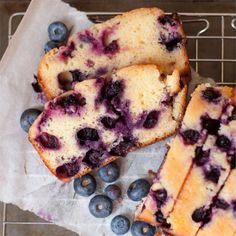 blueberry cheesecake bars on a cutting board with powdered sugar and fresh berries