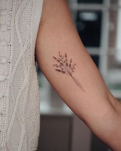 a woman's arm with a small flower tattoo on it