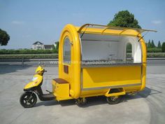 a small yellow mobile food cart parked next to a scooter