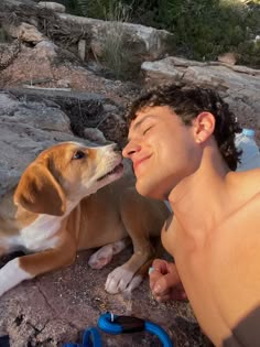 a man laying on top of a rocky hillside next to a brown and white dog