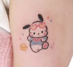 a small hello kitty tattoo on the thigh, with glasses and a bow around her neck