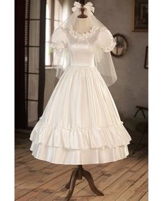 a white wedding dress on a mannequin in front of a window with a wooden floor