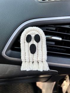 a close up of a car air freshener hanging from the dash board with black and white decorations on it