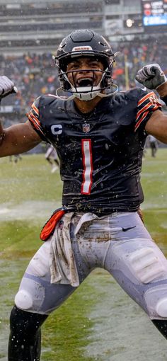 a football player holding his arms out in the rain