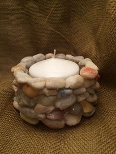 a lit candle sitting on top of a pile of rocks next to a brown cloth