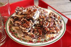 a plate full of pecans and chocolate on a red tray next to a glass of water