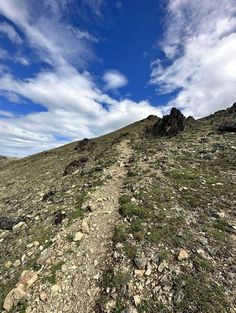 there is a trail going up the side of a hill with rocks and grass on it