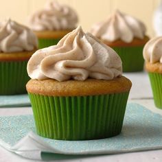 cupcakes with white frosting on top sitting on a blue napkin next to other cupcakes