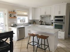 a kitchen with two stools in front of an island