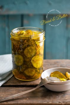 pickled cucumbers in a glass jar with a spoon on a wooden table