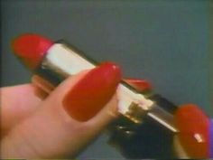 a hand holding a red and white lipstick in it's left thumbnails