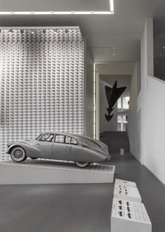 an old car is on display in a room with white walls and grey flooring